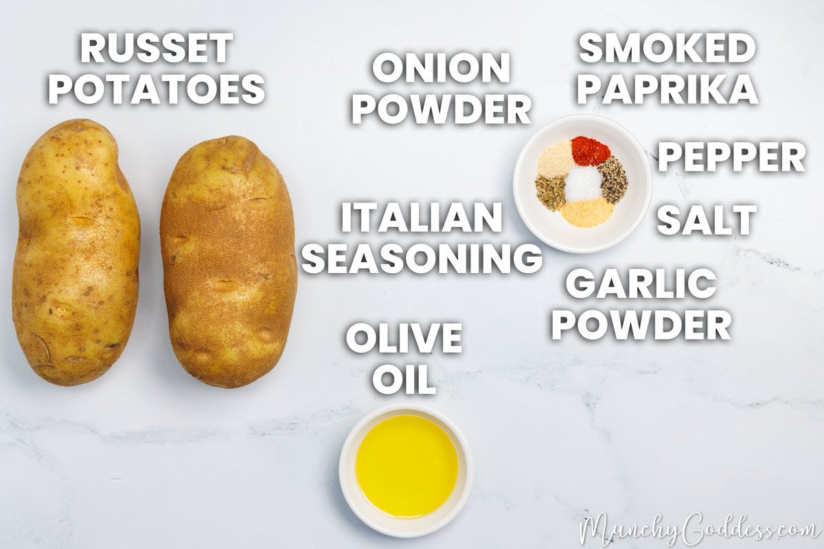 Oven baked potato slices recipe ingredients in various dishes on a white marble surface: russet potatoes, olive oil, salt, ground black pepper, garlic powder, onion powder, smoked paprika, Italian seasoning.