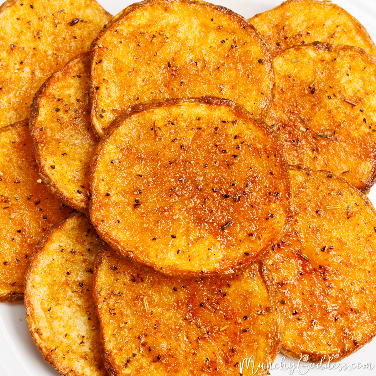 Overlapping oven baked potato slices on a white plate.