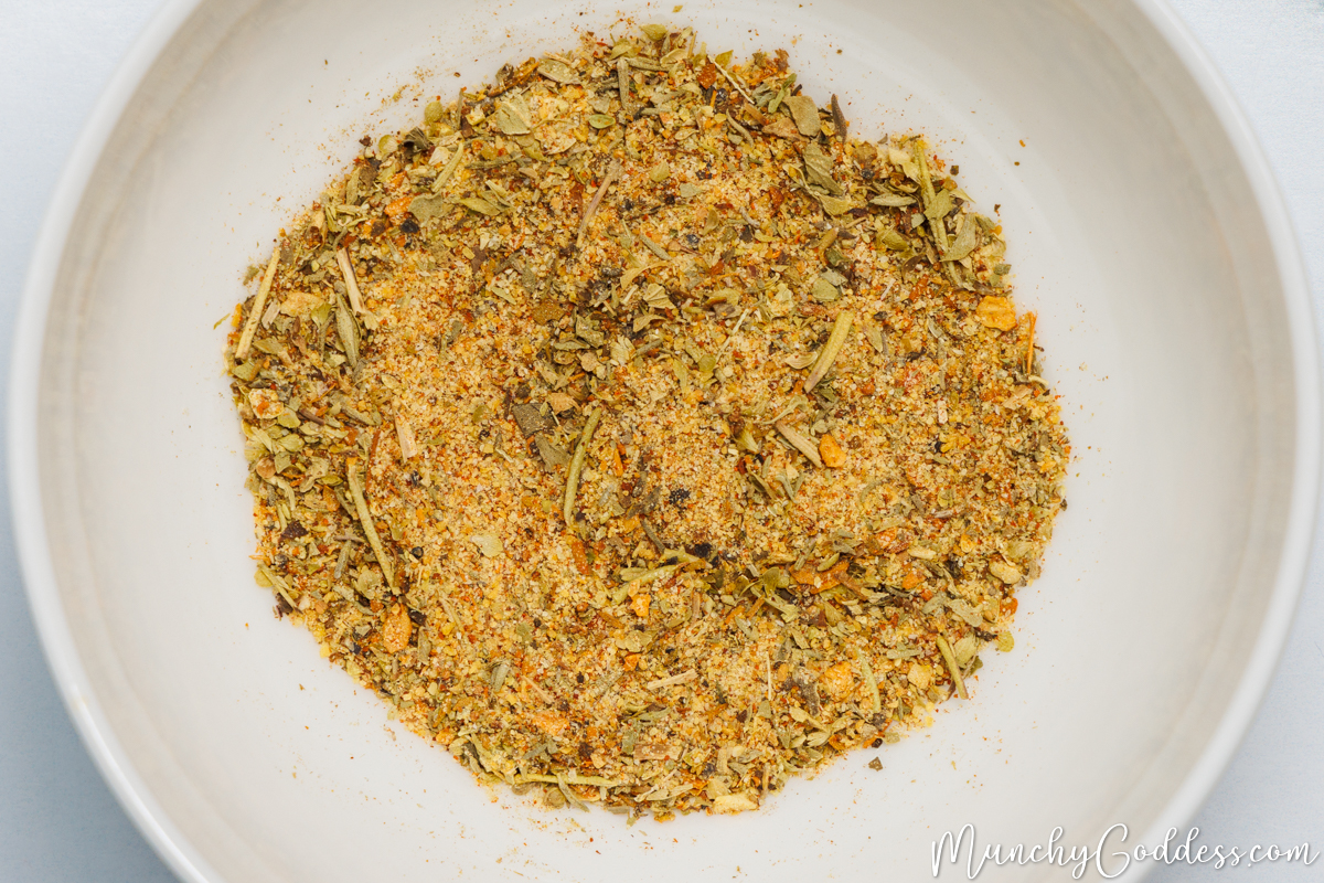 Cajun seasoning, Italian seasoning, lemon pepper seasoning, and garlic powder blended in an off white bowl.