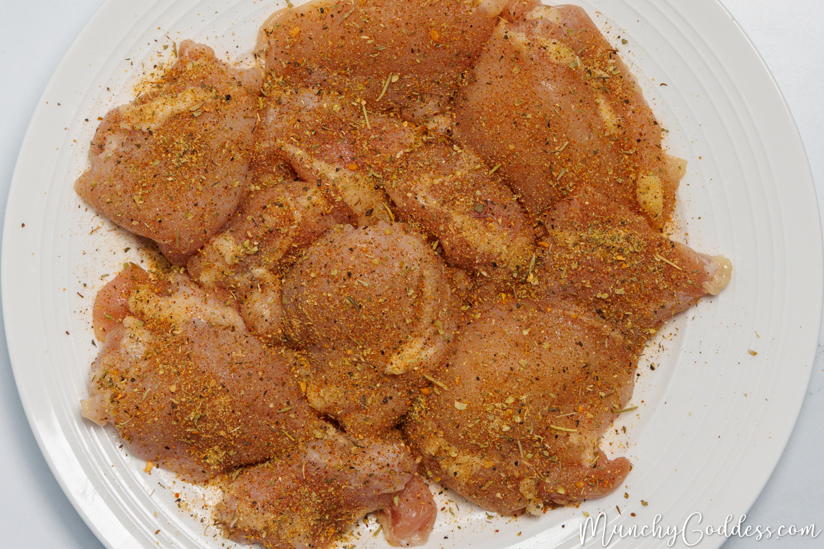 Cajun seasoned chicken thighs on an off white plate.