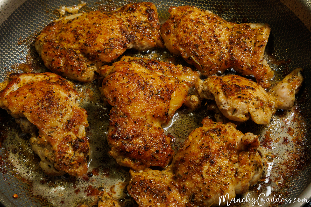 Cajun chicken thighs rich in color in a butter sauce inside a skillet.