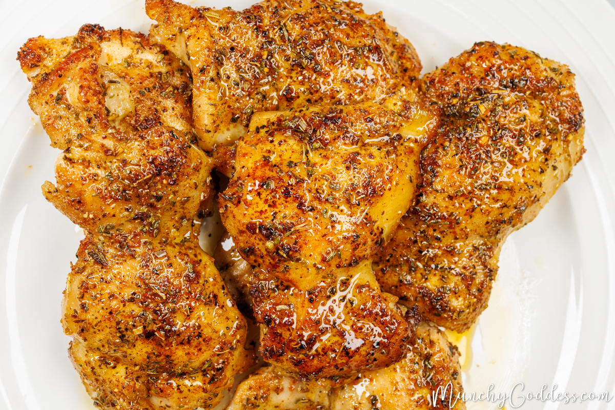 Cajun butter chicken thighs resting on an off white plate.