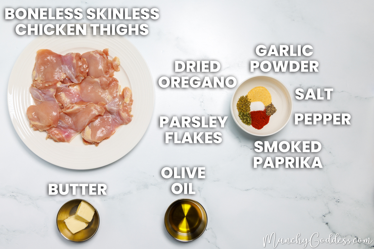 Pan seared chicken thighs recipe ingredients in various dishes on a white marble surface: boneless skinless chicken thighs, butter, olive oil, dried oregano, parsley flakes, smoked paprika, salt, ground black pepper, and garlic powder.