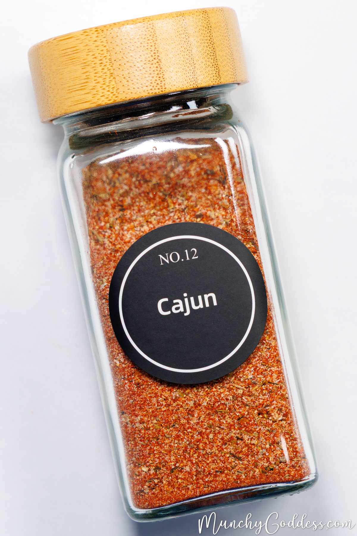 Cajun seasoning inside a clear glass spice jar with a wooden lid.