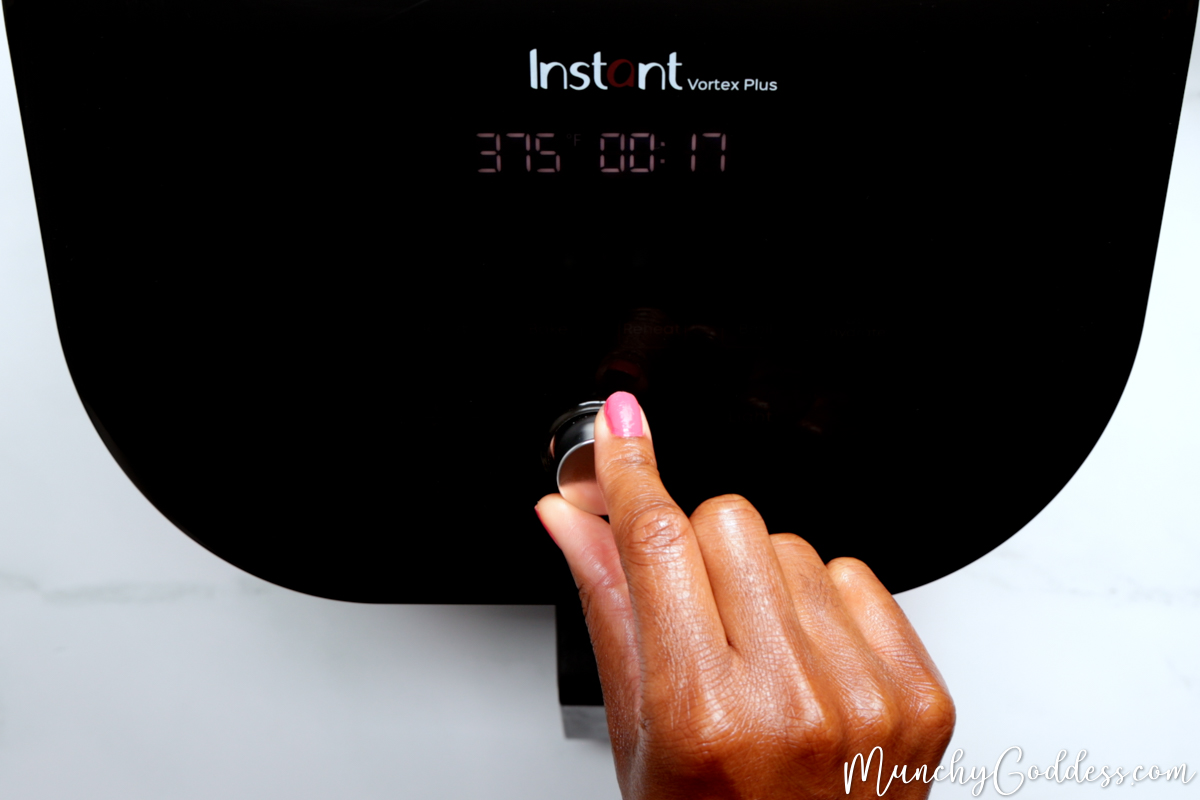 Black air fryer panel with a silver dial set to 375 degrees Fahrenheit for 17 minutes.