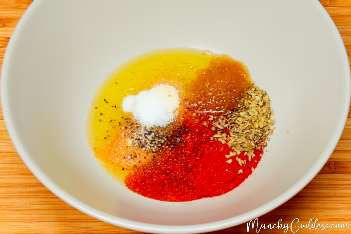 Olive oil, Italian seasoning, garlic powder, salt, ground black pepper, smoked paprika, brown sugar, and onion powder in a light gray bowl.