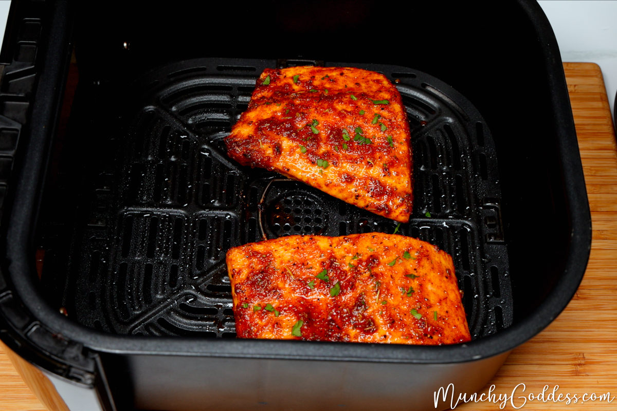 Salmon fillets in a black air fryer basket perfectly seasoned and cooked.