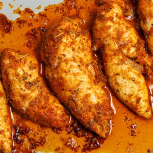 Baked chicken tenderloins perfectly seasoned and cooked side by side in a baking dish.