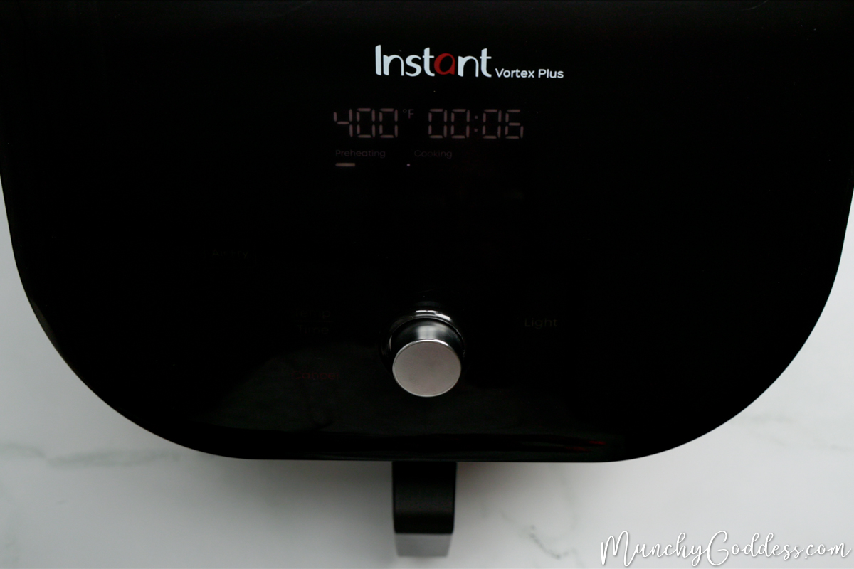Black air fryer panel with a silver dial set to 400 degrees Fahrenheit for 6 minutes.