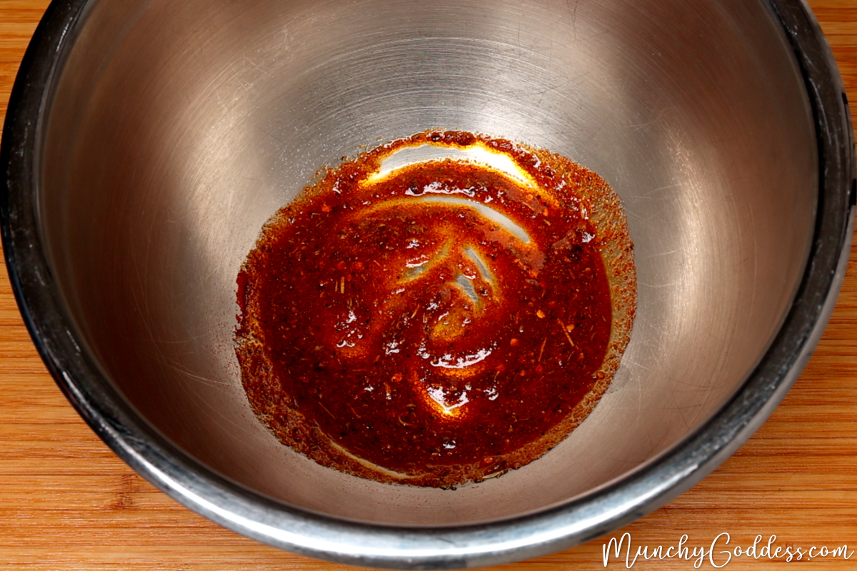 Melted butter, olive oil, salt, ground black pepper, onion powder, garlic powder, Italian seasoning, smoked paprika, and red pepper flakes blended in a silver mixing bowl.