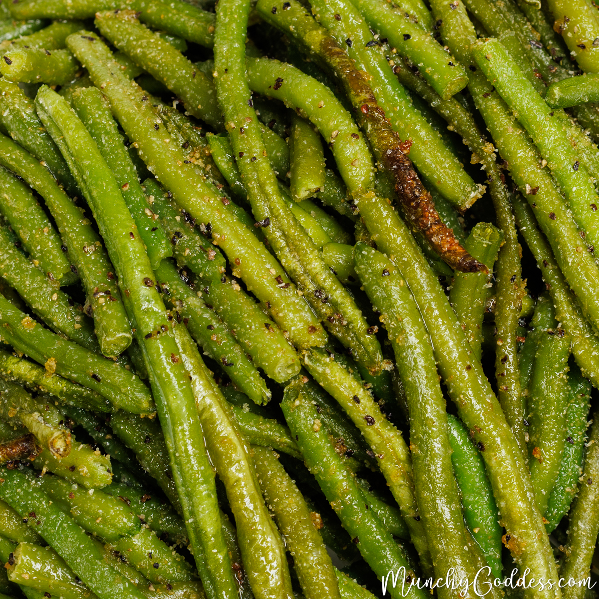 Roasted frozen green beans seasoned with salt, ground black pepper, garlic powder, and onion powder piled on top of each other.