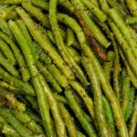 Roasted frozen green beans seasoned with salt, ground black pepper, garlic powder, and onion powder piled on top of each other.