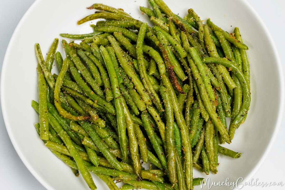 Seasoned and roasted frozen green beans in an off-white bowl.