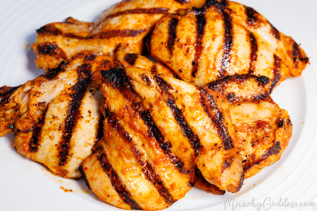 Grilled chicken thighs with dark, parallel sear marks resting on an off-white plate.