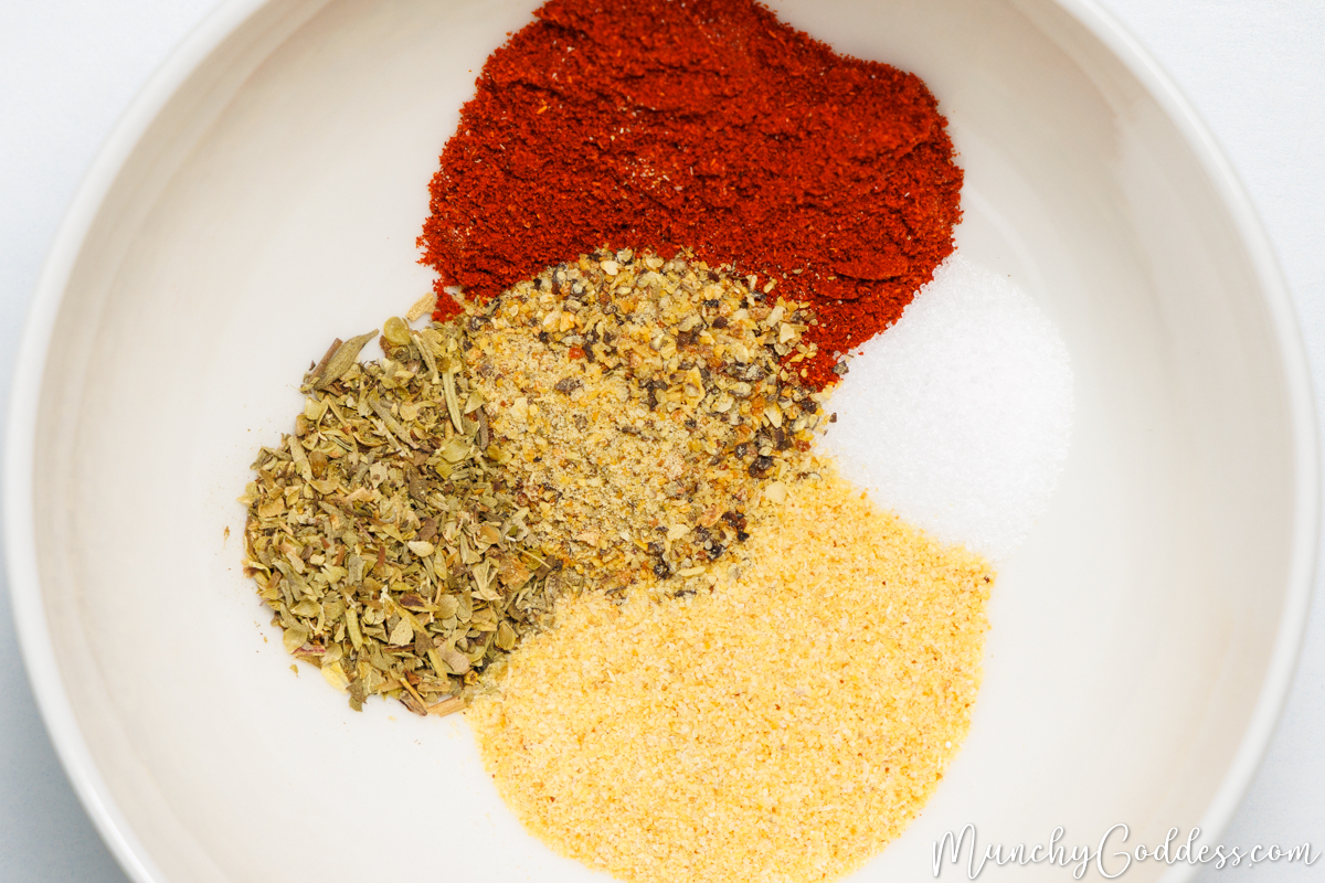 Smoked paprika, salt, garlic powder, Italian seasoning, and lemon pepper seasoning neatly placed in an off-white bowl.