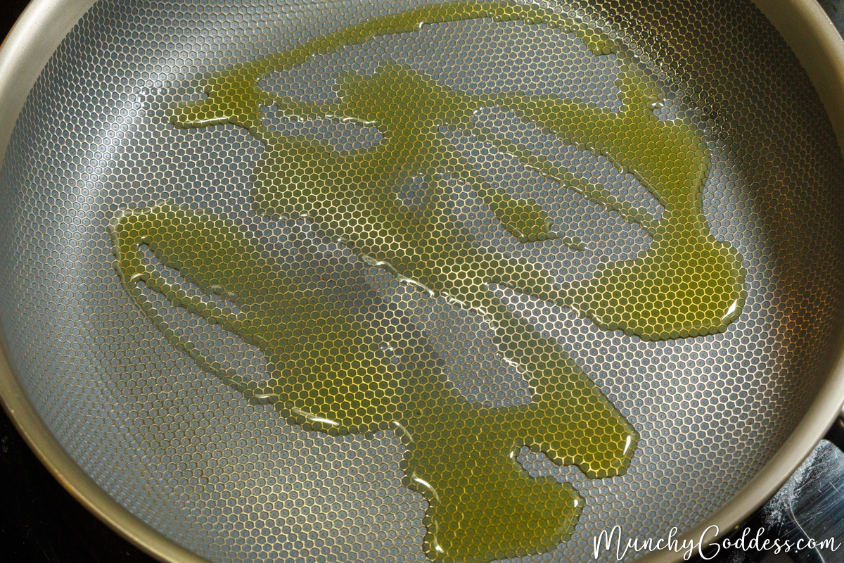 Olive oil drizzled in a heated skillet with a textured honeycomb pattern.