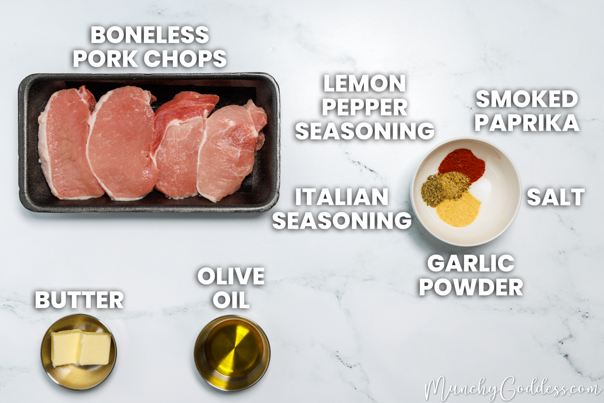 Lemon pepper pork chops recipe ingredients in various dishes on a white marble surface: boneless pork chops, butter, olive oil, lemon pepper seasoning, smoked paprika, salt, garlic powder, and Italian seasoning.