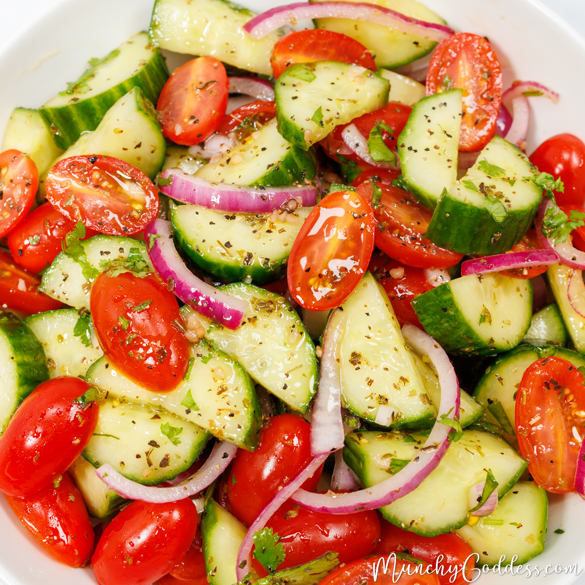 Cucumber tomato salad with halved cucumber slices, halved cherry tomatoes, and slices of red onion tossed in a homemade salad dressing.