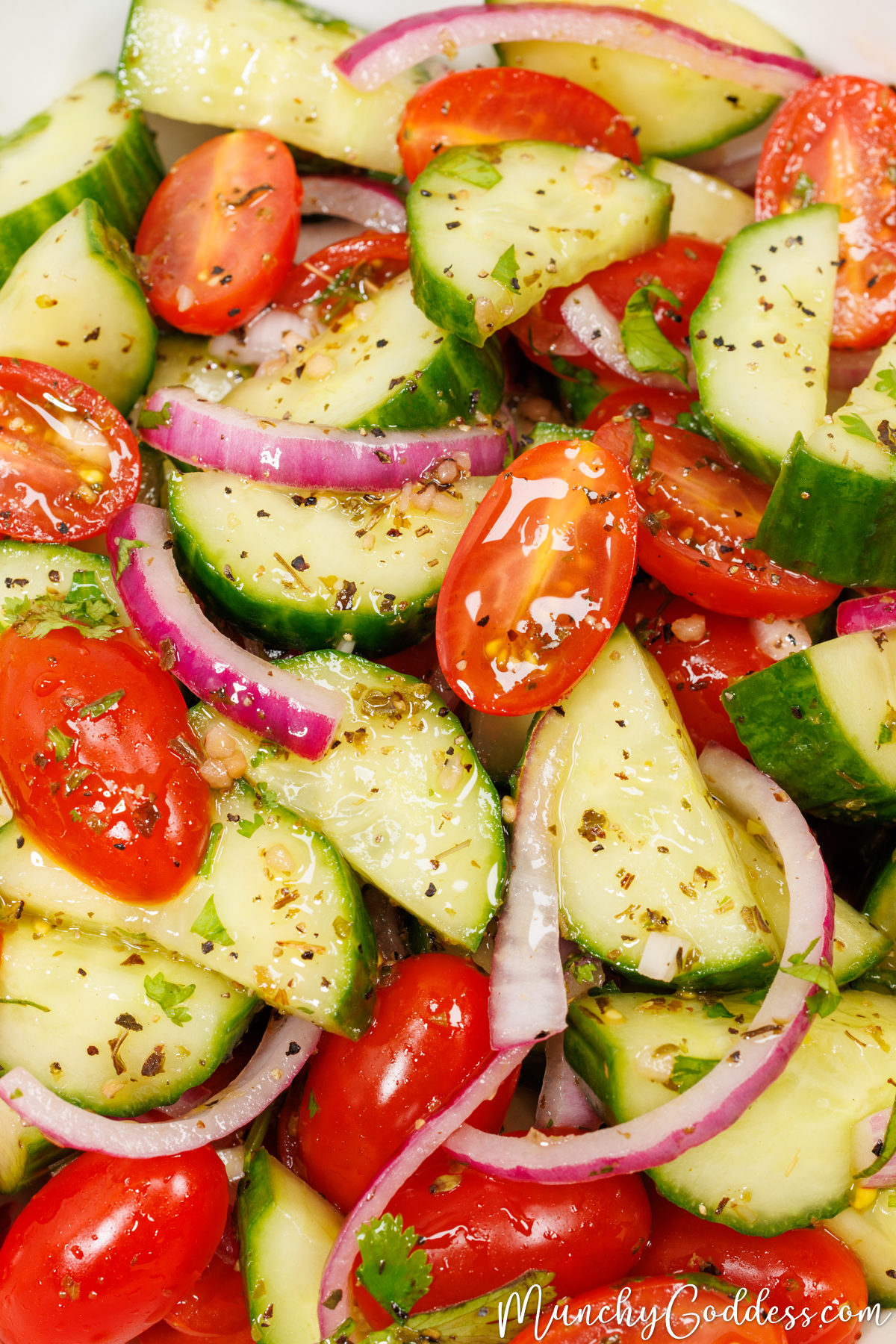 Fresh cucumber tomato salad featuring crisp cucumber slices, juicy halved cherry tomatoes, and slices of red onion tossed in a homemade salad dressing.