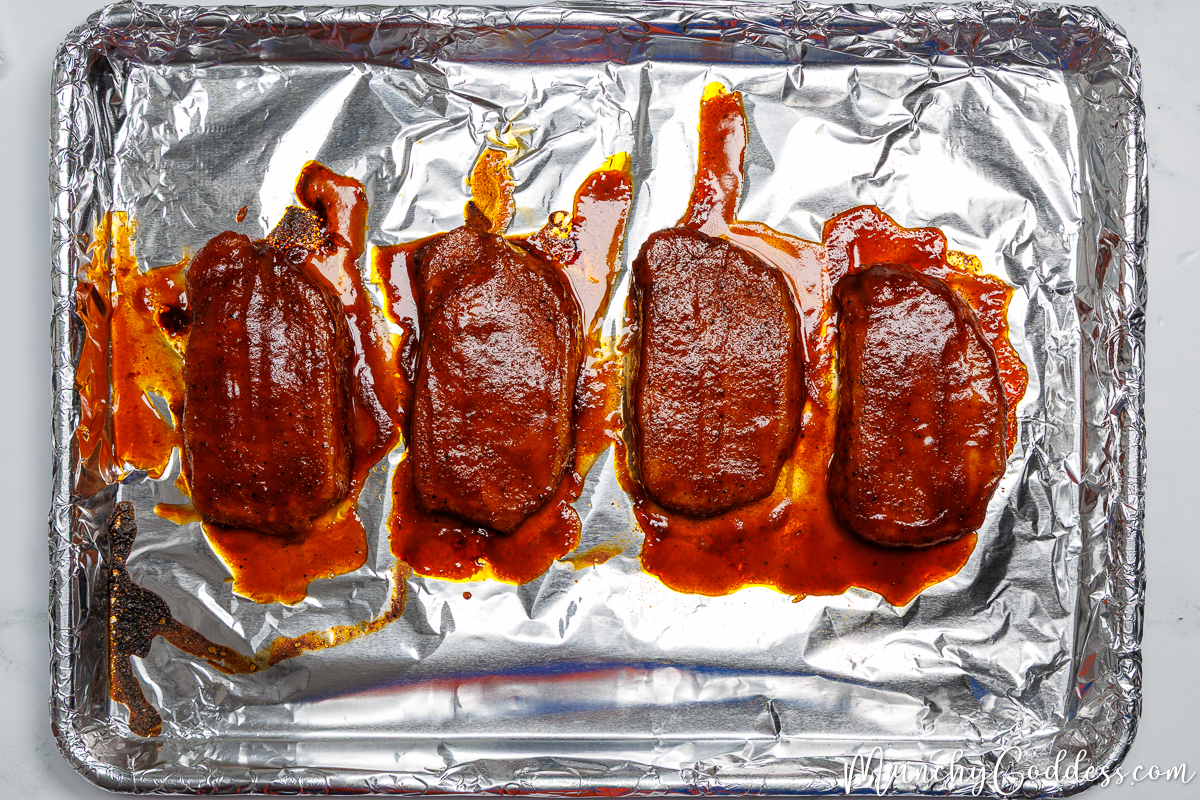 Baked bbq pork chops on a foil-lined sheet pan.