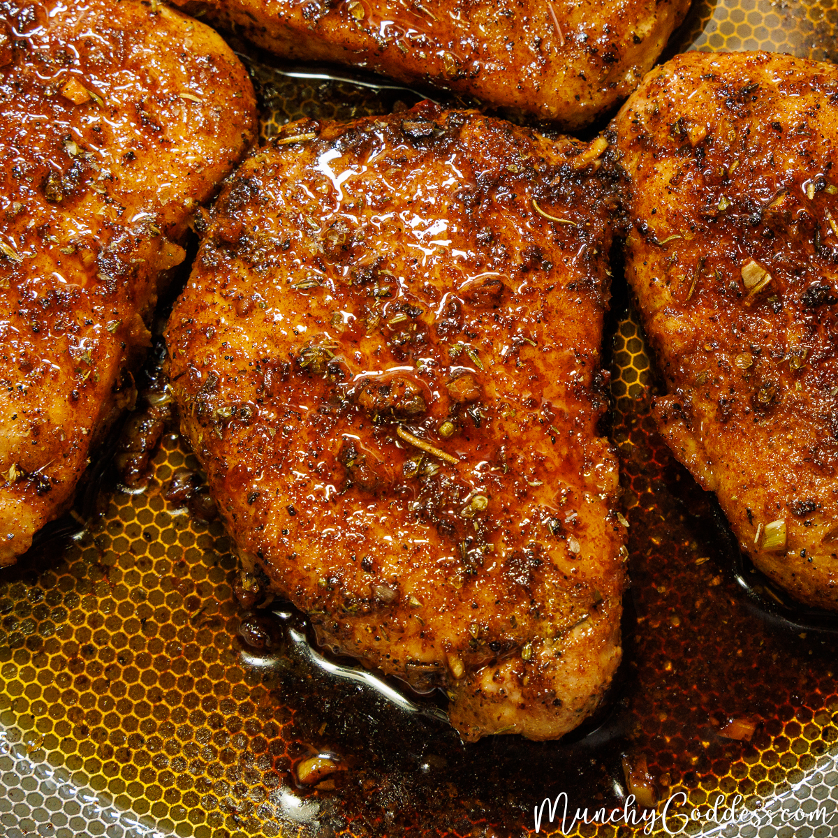 Four perfectly seared, juicy pork chops resting in a skillet, glistening with garlic butter and herbs.