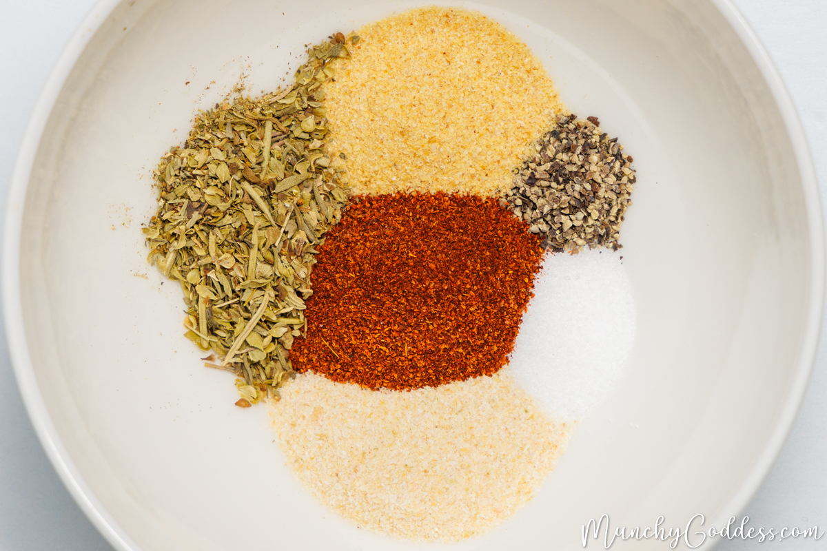 Italian seasoning, garlic powder, ground black pepper, salt, onion powder, and smoked paprika neatly placed in an off-white bowl.