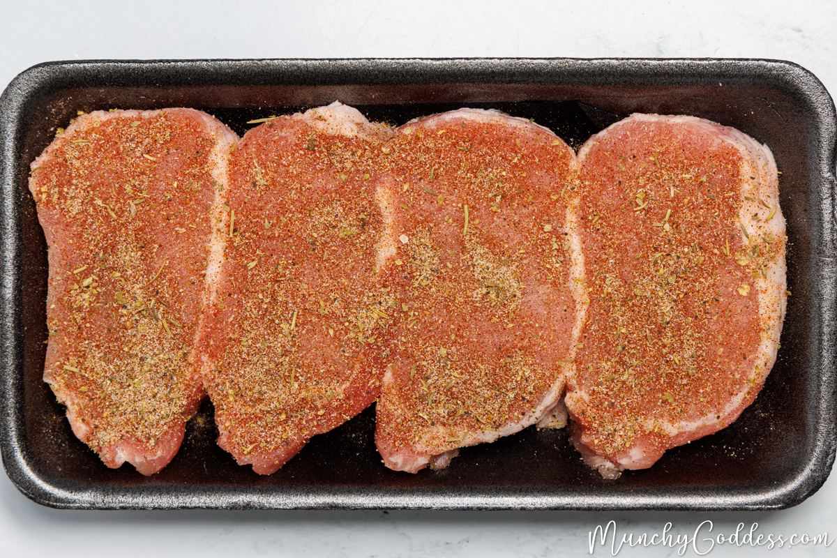 Boneless pork chops in a black foam meat tray seasoned on all sides.