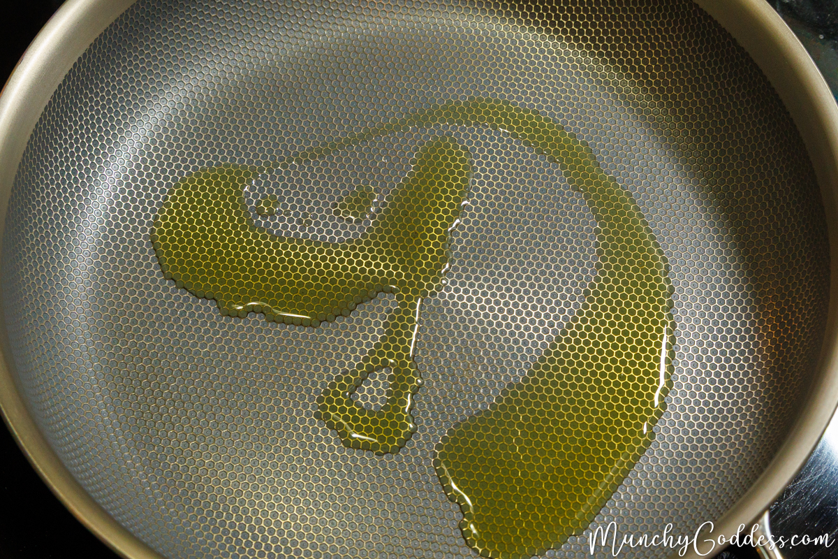 Olive oil heating in the center of a skillet.