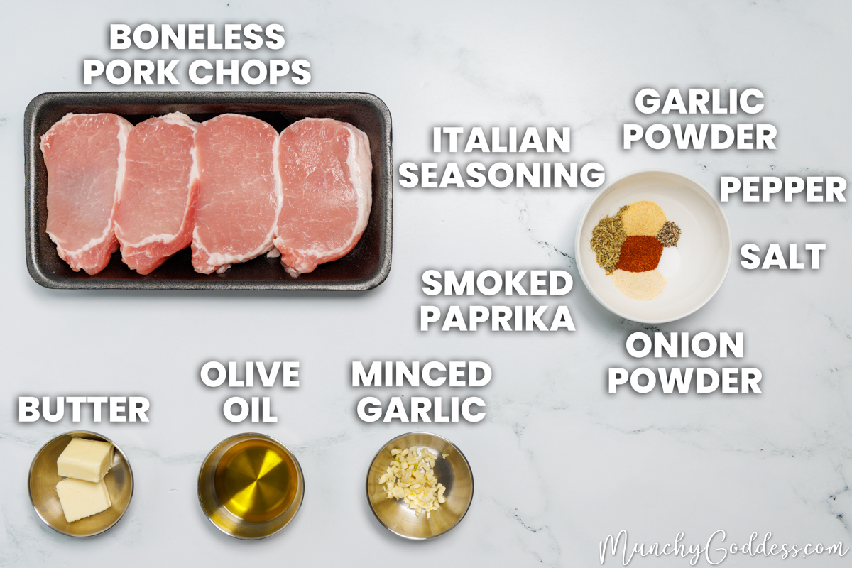Garlic butter pork chops recipe ingredients in various dishes on a white marble surface: boneless pork chops, butter, olive oil, minced garlic, Italian seasoning, garlic powder, ground black pepper, salt, onion powder, and smoked paprika.